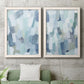 Set of two white barnwood framed canvas prints depicting a coordinated art pair of fragmented pale blue green gray and white brush blocks rendered as cool-toned geometric abstracts above a sofa in a modern living room.