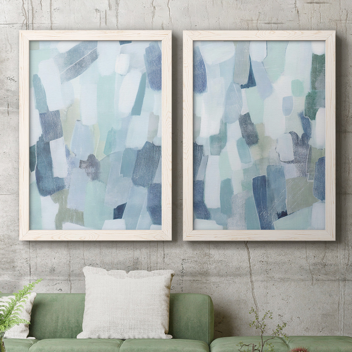 Set of two white barnwood framed canvas prints depicting a coordinated art pair of fragmented pale blue green gray and white brush blocks rendered as cool-toned geometric abstracts above a sofa in a modern living room.