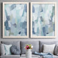Set of two white barnwood framed canvas prints depicting paired cool-toned geometric abstracts with overlapping rectangular marks and softly weathered paint above a sofa in a contemporary living room.