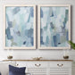 Set of two white barnwood framed canvas prints depicting a coordinated art pair of fragmented pale blue green gray and white brush blocks rendered as cool-toned geometric abstracts above a dining room sideboard.
