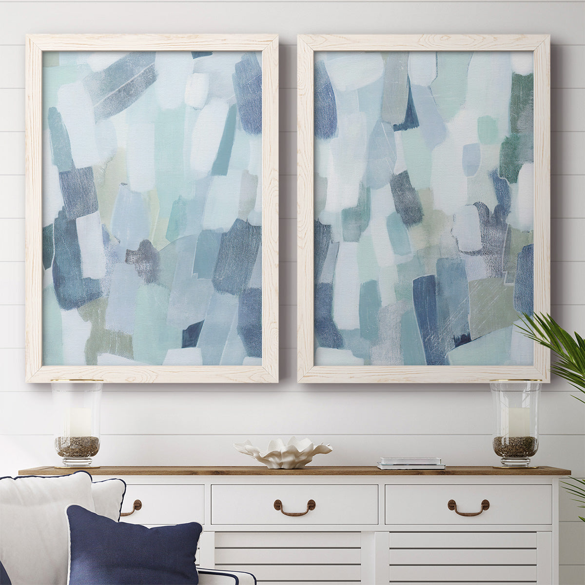 Set of two white barnwood framed canvas prints depicting a coordinated art pair of fragmented pale blue green gray and white brush blocks rendered as cool-toned geometric abstracts above a dining room sideboard.
