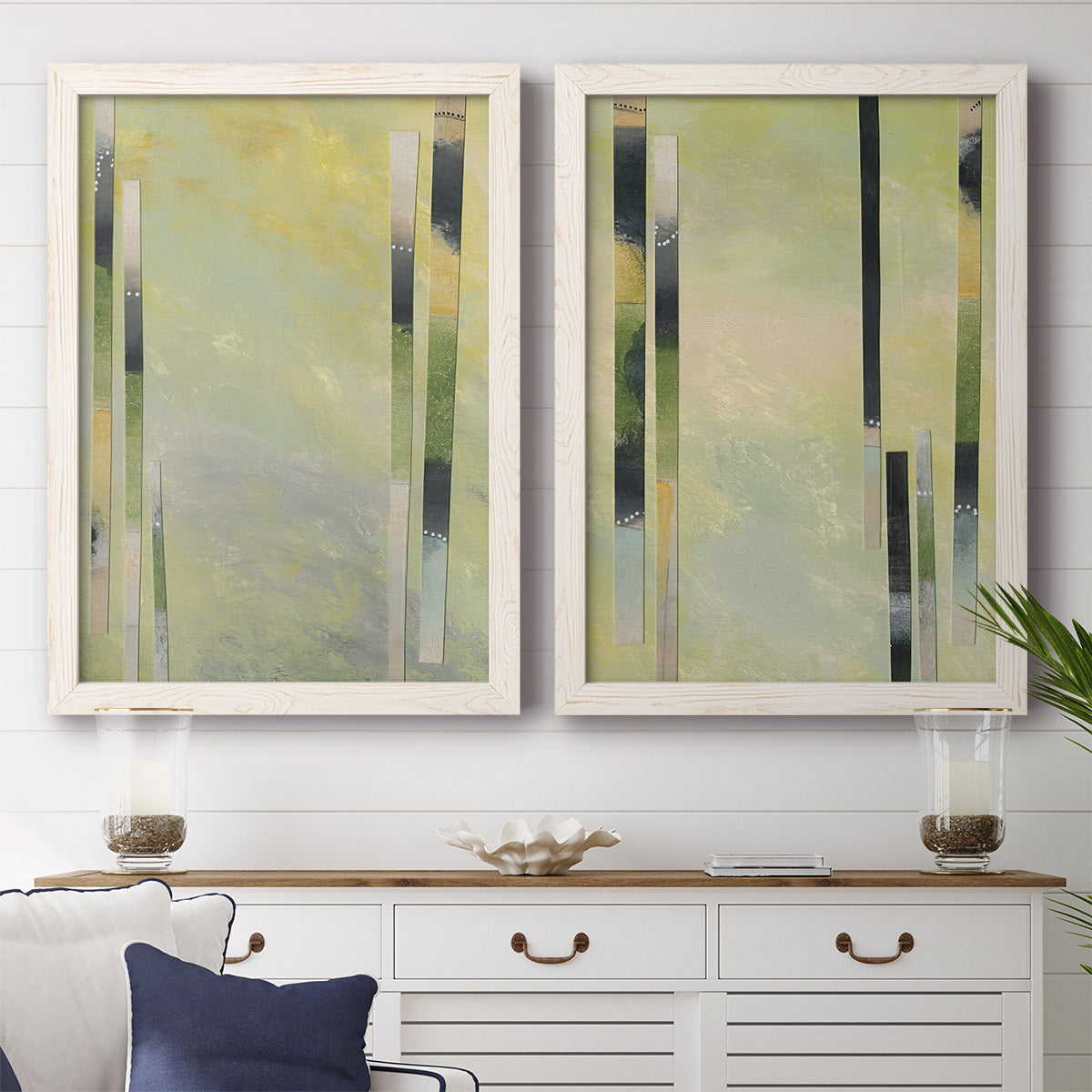 Set of two white barnwood framed canvas prints depicting a coordinated art pair of vertical black gray and olive bars rendered as minimalist architectural abstracts above a dining room sideboard.