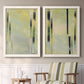 Set of two white barnwood framed canvas prints depicting two minimalist architectural abstracts featuring vertical black gray and olive bars above a sideboard in a cozy sitting room.