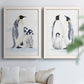Set of two white barnwood framed canvas prints depicting black white and yellow birds standing on pale icy ground arranged across two complementary compositions above a sofa in a bright living space.