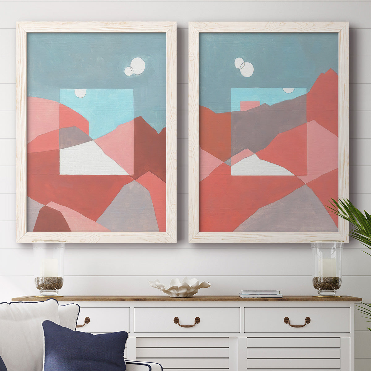 Set of two white barnwood framed canvas prints depicting a coordinated art pair of layered red coral and turquoise desert-like geometry rendered as modern abstract landscapes above a dining room sideboard.