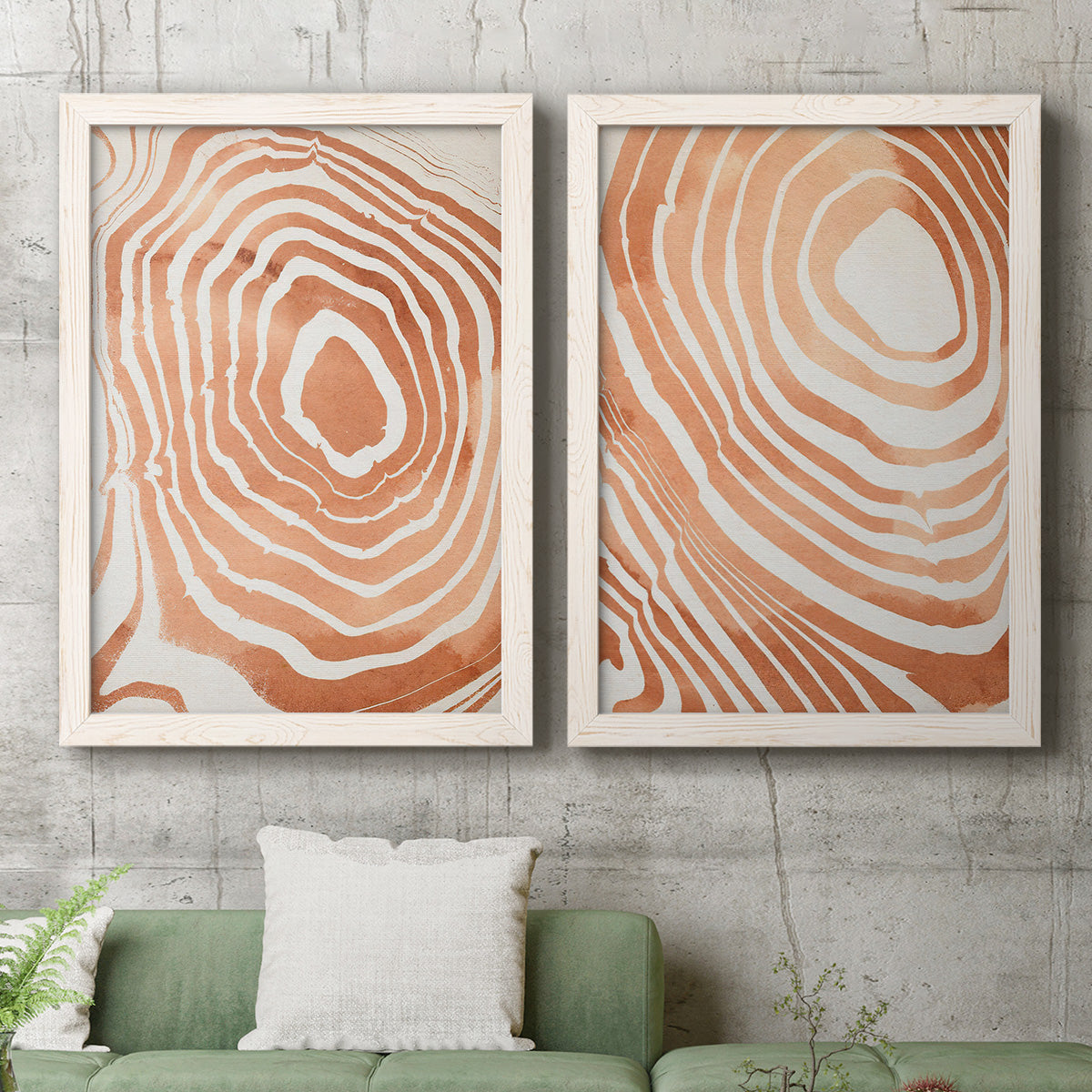 Set of two white barnwood framed canvas prints depicting a coordinated art pair of concentric wood-grain rings and rippling contour lines rendered as minimalist marbled pattern abstracts above a sofa in a modern living room.