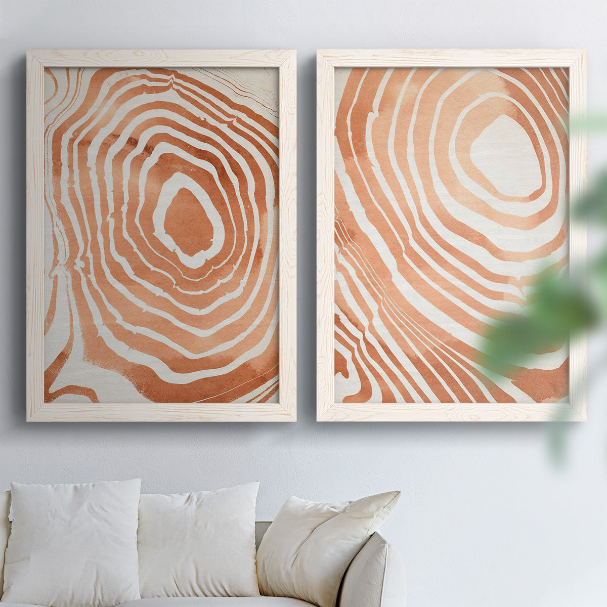 Set of two white barnwood framed canvas prints depicting warm terracotta lines, cream negative space, and organic nested curves arranged across two complementary compositions above a sofa in a bright living space.