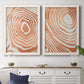 Set of two white barnwood framed canvas prints depicting a coordinated art pair of concentric wood-grain rings and rippling contour lines rendered as minimalist marbled pattern abstracts above a dining room sideboard.