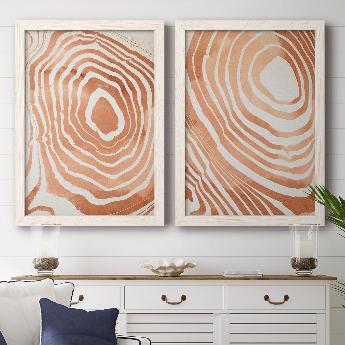 Set of two white barnwood framed canvas prints depicting a coordinated art pair of concentric wood-grain rings and rippling contour lines rendered as minimalist marbled pattern abstracts above a dining room sideboard.
