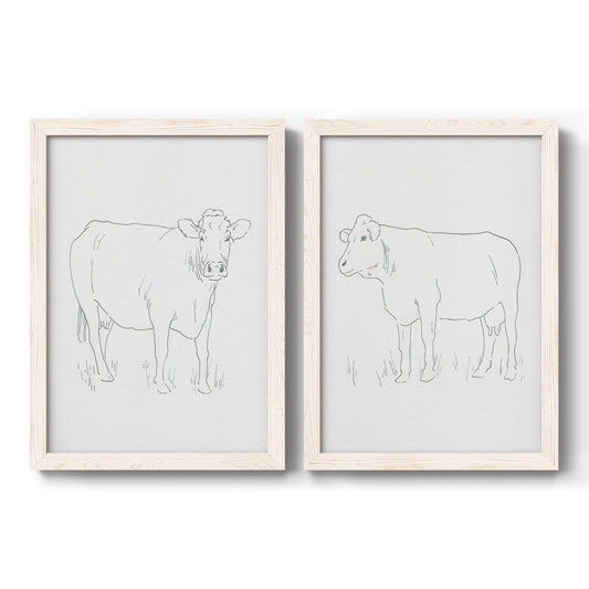Set of two white barnwood framed canvas prints featuring two minimalist livestock sketches featuring simple contour drawings of standing cows.