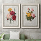 Set of two white barnwood framed canvas prints depicting a coordinated art pair of vintage mixed-flower bouquets on distressed paper rendered as traditional botanical collage prints above a sofa in a modern living room.