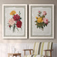 Set of two white barnwood framed canvas prints depicting two traditional botanical collage prints featuring vintage mixed-flower bouquets on distressed paper above a sideboard in a cozy sitting room.