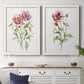 Set of two white barnwood framed canvas prints depicting a coordinated art pair of two airy wildflower stems with pink and burgundy blossoms rendered as traditional watercolor flower studies above a dining room sideboard.
