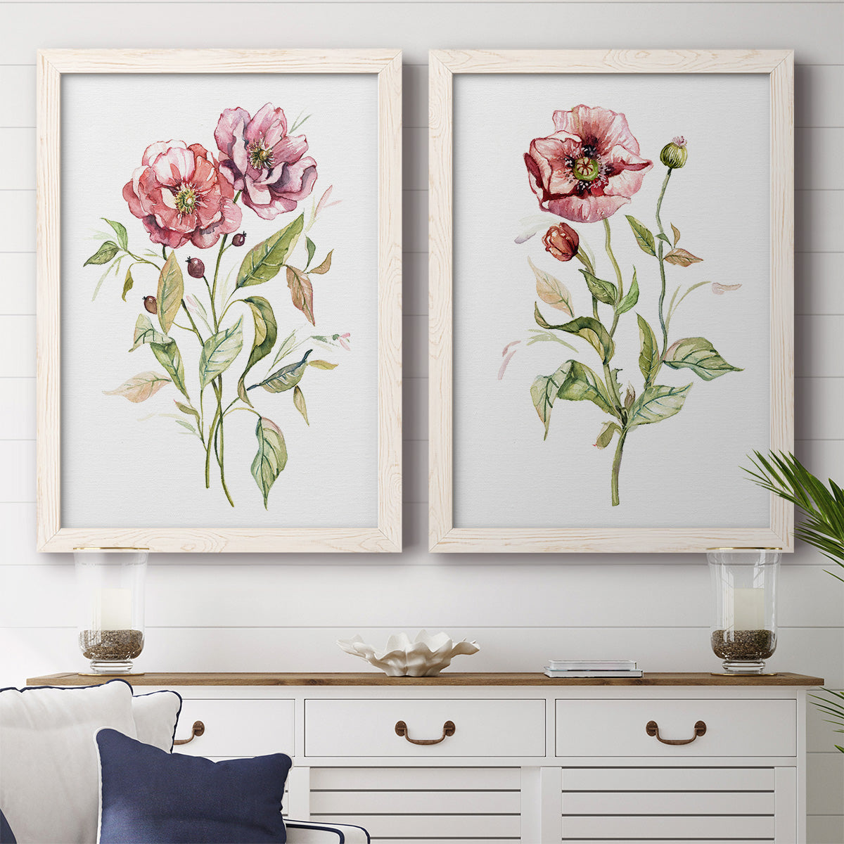 Set of two white barnwood framed canvas prints depicting a coordinated art pair of two airy wildflower stems with pink and burgundy blossoms rendered as traditional watercolor flower studies above a dining room sideboard.