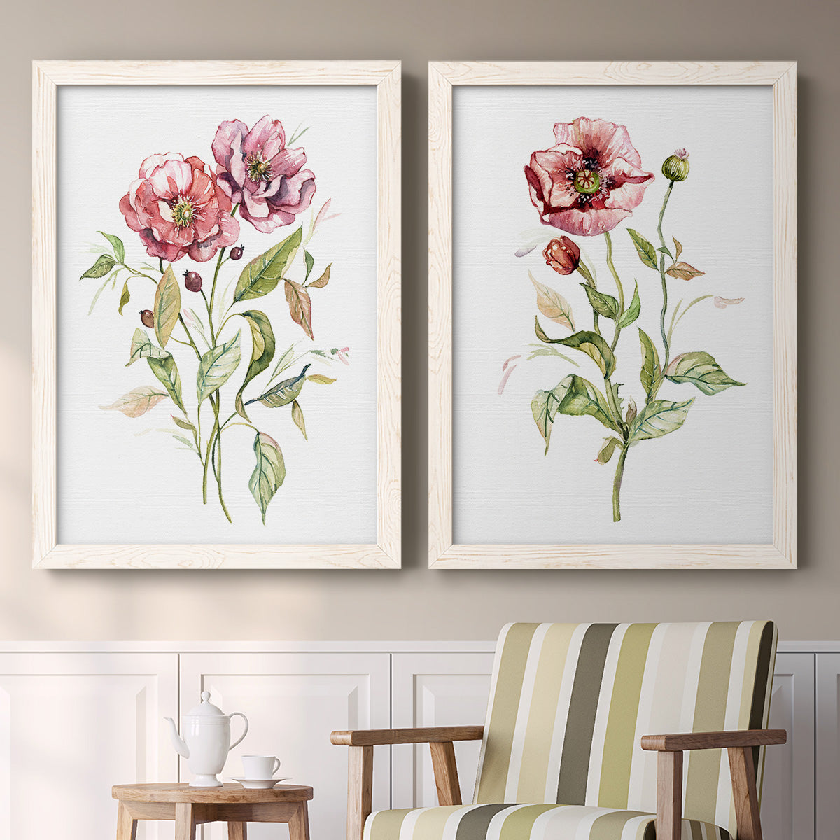 Set of two white barnwood framed canvas prints depicting two traditional watercolor flower studies featuring two airy wildflower stems with pink and burgundy blossoms above a sideboard in a cozy sitting room.
