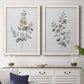 Set of two white barnwood framed canvas prints depicting a coordinated art pair of delicate eucalyptus branches with rounded leaves rendered as minimalist watercolor botanical studies above a dining room sideboard.