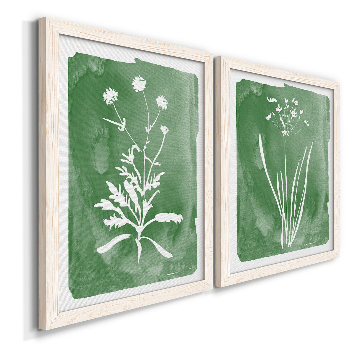 Angled view of a set of two white barnwood framed canvas prints featuring two rustic minimalist botanical studies featuring delicate wildflower and leafy stems.