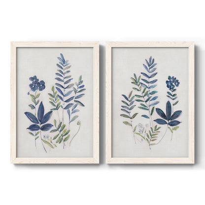 Set of two white barnwood framed canvas prints featuring two rustic botanical illustrations featuring blue fern fronds and small woodland flowers.