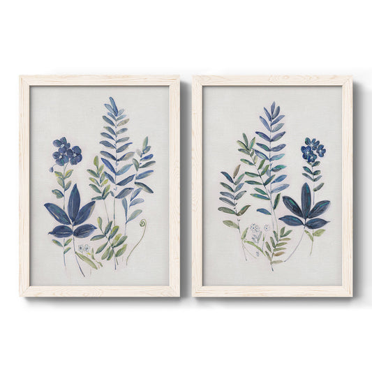 Set of two white barnwood framed canvas prints featuring two rustic botanical illustrations featuring blue fern fronds and small woodland flowers.
