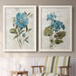 Set of two white barnwood framed canvas prints depicting two rustic floral illustrations featuring blue peony and hydrangea-like blooms over vintage script above a sideboard in a cozy sitting room.