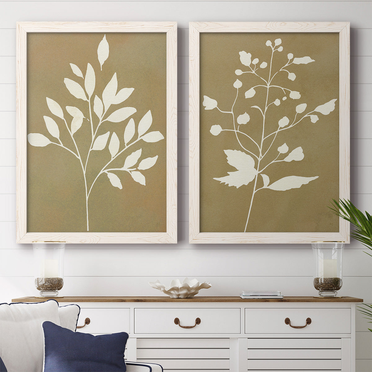 Set of two white barnwood framed canvas prints depicting a modern plant pair of cream branches berries and leaves on muted ochre fields above a dining room sideboard.