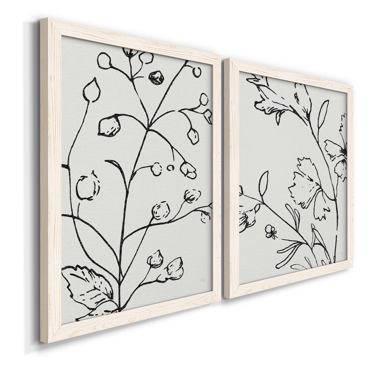 Angled view of a set of two white barnwood framed canvas prints featuring two minimalist botanical line art featuring black contour drawings of leaves and flowers.