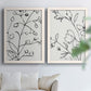Set of two white barnwood framed canvas prints depicting fine monochrome outlines, cropped stems, and clean white fields arranged across two complementary compositions above a sofa in a bright living space.