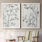 Set of two white barnwood framed canvas prints depicting two minimalist botanical line art featuring black contour drawings of leaves and flowers above a sideboard in a cozy sitting room.