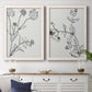 Set of two white barnwood framed canvas prints depicting a coordinated art pair of black line drawings of wildflowers and leaves rendered as minimalist botanical sketches above a dining room sideboard.