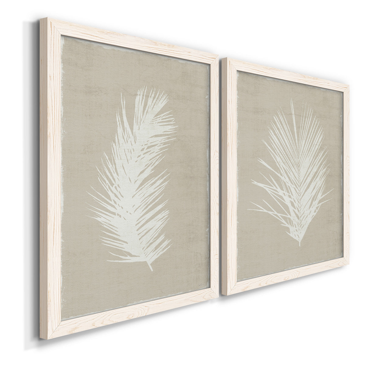 Angled view of a set of two white barnwood framed canvas prints featuring two minimalist tropical botanical prints featuring white palm frond silhouettes.