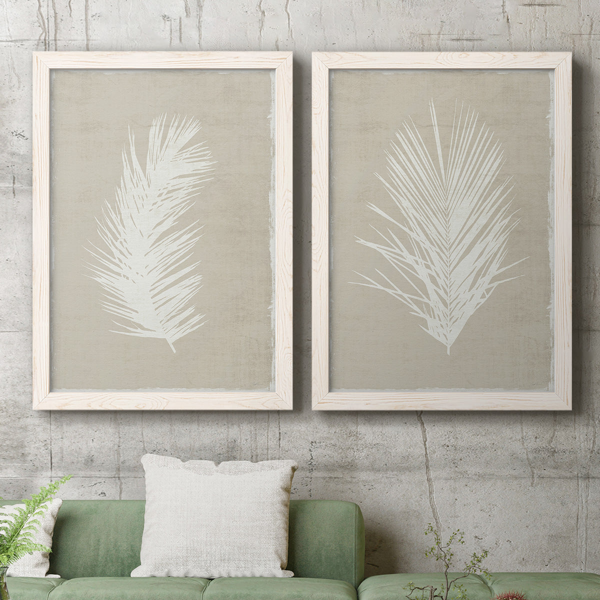 Set of two white barnwood framed canvas prints depicting a coordinated art pair of white palm frond silhouettes rendered as minimalist tropical botanical prints above a sofa in a modern living room.
