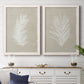 Set of two white barnwood framed canvas prints depicting a coordinated art pair of white palm frond silhouettes rendered as minimalist tropical botanical prints above a dining room sideboard.