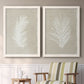 Set of two white barnwood framed canvas prints depicting two minimalist tropical botanical prints featuring white palm frond silhouettes above a sideboard in a cozy sitting room.