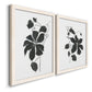 Angled view of a set of two white barnwood framed canvas prints featuring two minimalist botanical prints featuring black leafy vine silhouettes.