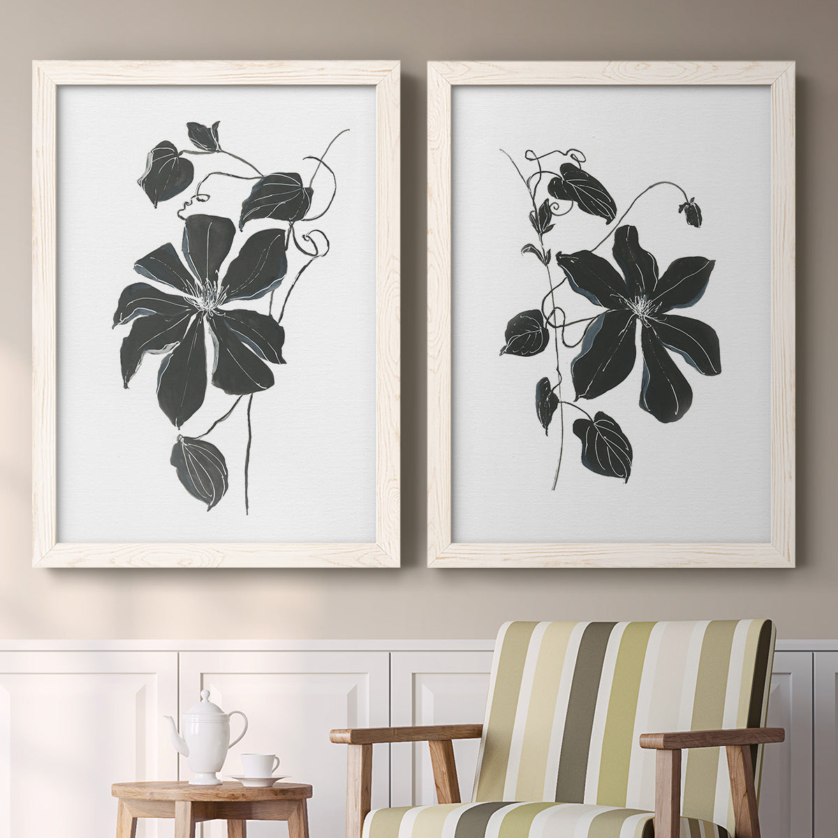 Set of two white barnwood framed canvas prints depicting two minimalist botanical prints featuring black leafy vine silhouettes above a sideboard in a cozy sitting room.