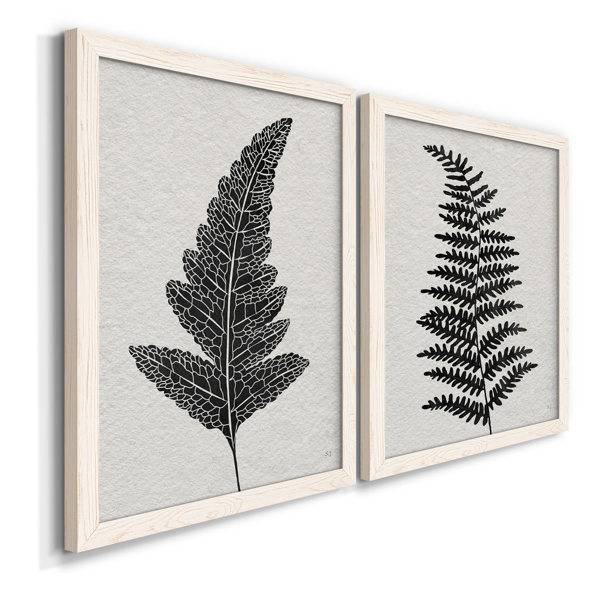 Angled view of a set of two white barnwood framed canvas prints featuring two minimalist botanical prints featuring black fern leaf silhouettes.