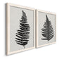 Angled view of a set of two white barnwood framed canvas prints featuring two minimalist botanical prints featuring black fern leaf silhouettes.
