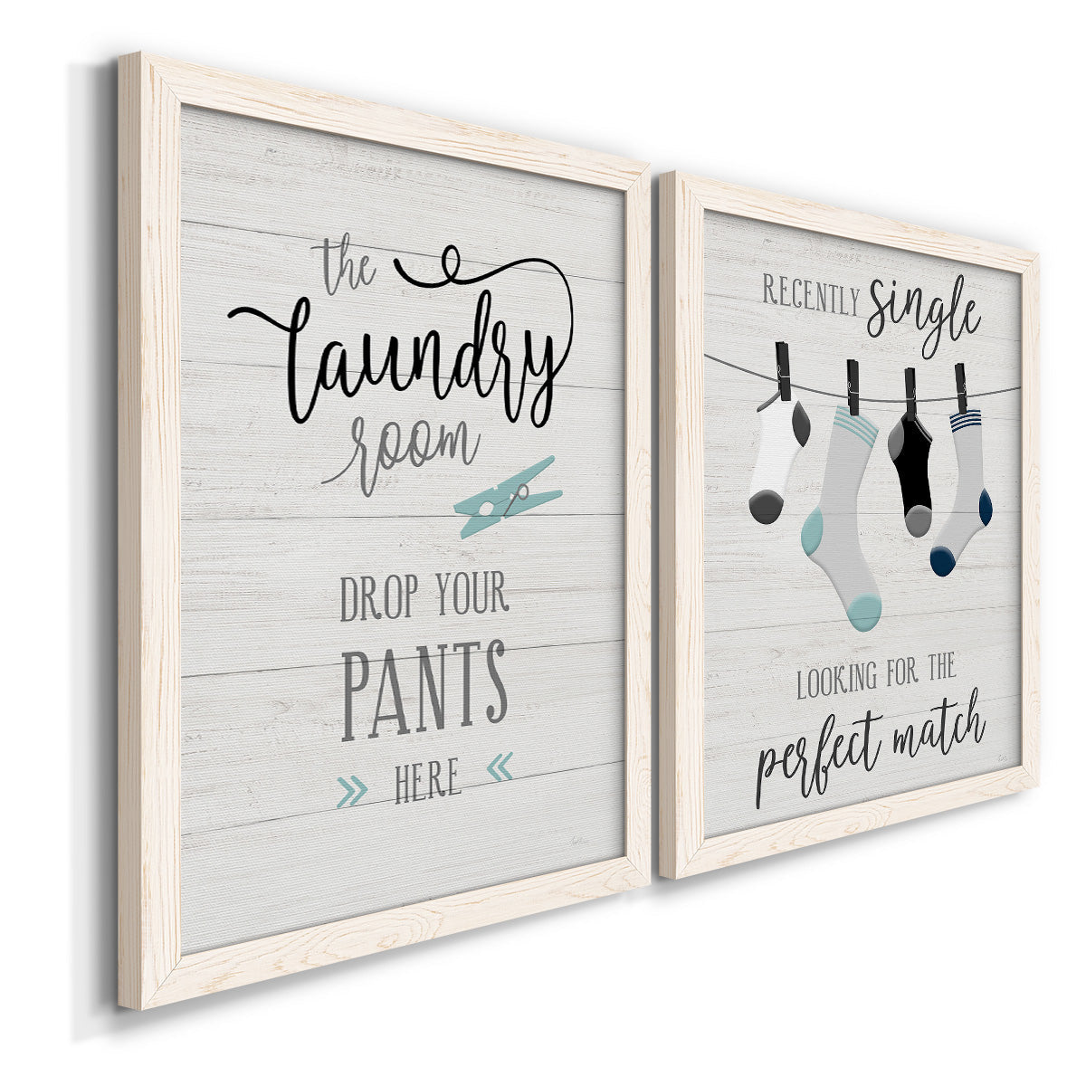 Angled view of a set of two white barnwood framed canvas prints featuring two rustic typographic wall art featuring humorous laundry-room sayings and clothing icons.