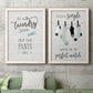 Set of two white barnwood framed canvas prints depicting a coordinated art pair of humorous laundry-room sayings and clothing icons rendered as rustic typographic wall art above a sofa in a modern living room.