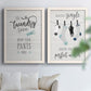 Set of two white barnwood framed canvas prints depicting hand-lettered phrases, socks hangers and laundry symbols on linen texture arranged across two complementary compositions above a sofa in a bright living space.