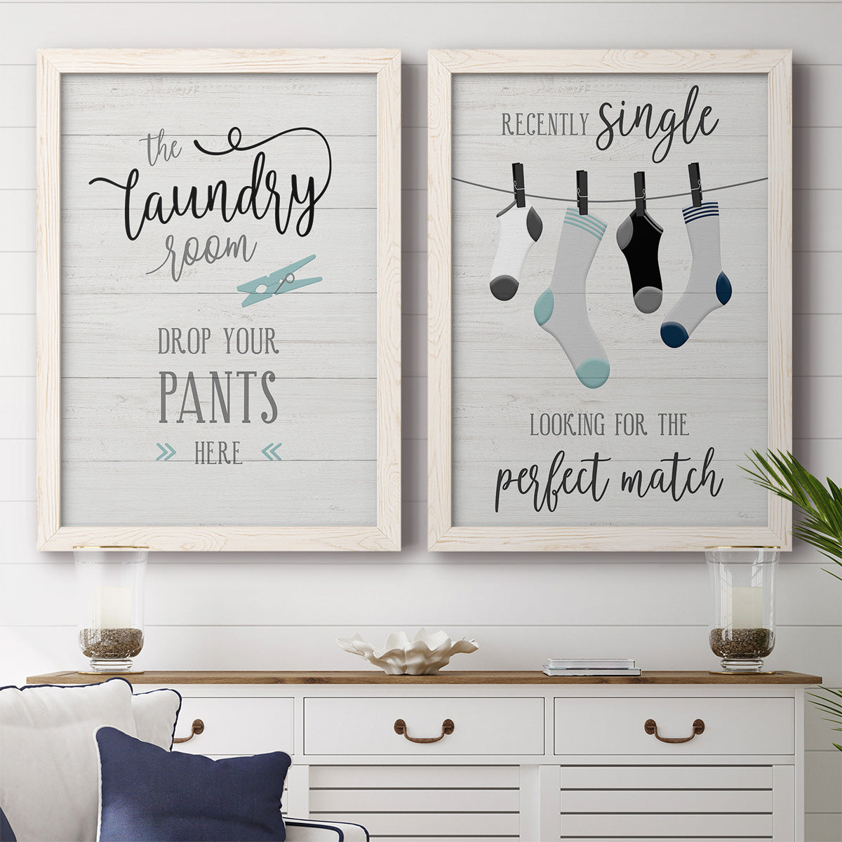 Set of two white barnwood framed canvas prints depicting a coordinated art pair of humorous laundry-room sayings and clothing icons rendered as rustic typographic wall art above a dining room sideboard.