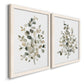 Angled view of a set of two white barnwood framed canvas prints featuring two minimalist watercolor botanical studies featuring delicate eucalyptus branches with rounded leaves.