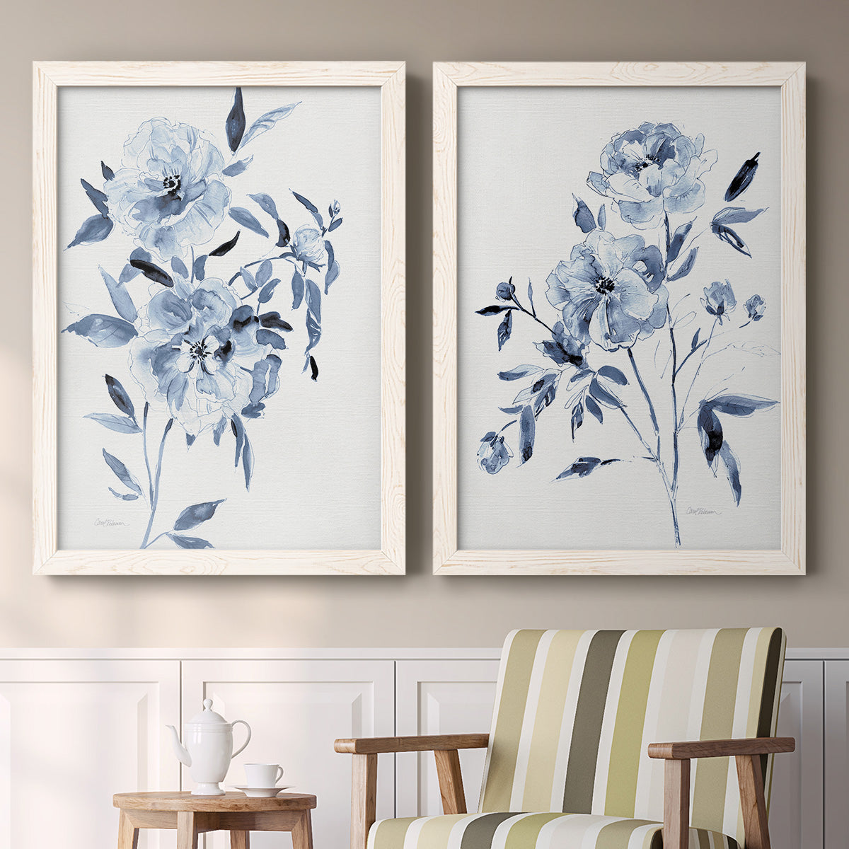 Set of two white barnwood framed canvas prints depicting two expressive watercolor botanical paintings featuring loose blue flowers and leafy branches above a sideboard in a cozy sitting room.