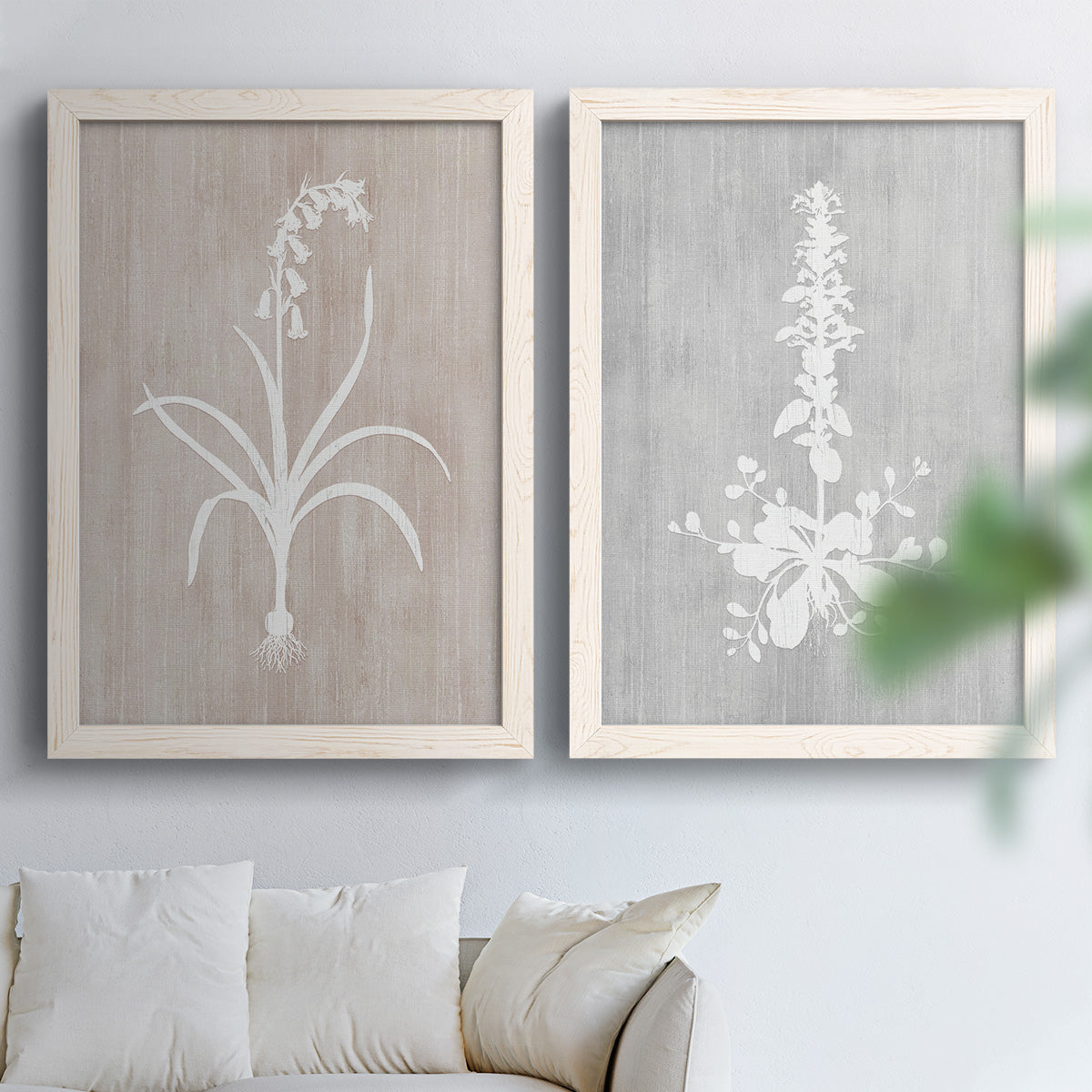 Set of two white barnwood framed canvas prints depicting delicate stems, leaves, and blossoms against gray taupe and pale blue panels arranged across two complementary compositions above a sofa in a bright living space.