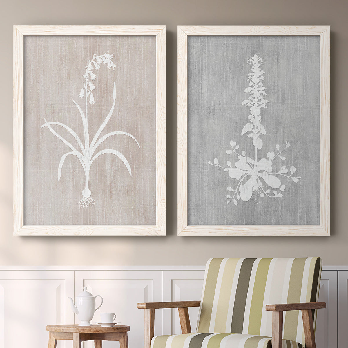 Set of two white barnwood framed canvas prints depicting two rustic minimalist botanical prints featuring white botanical silhouettes on softly weathered neutral backgrounds above a sideboard in a cozy sitting room.