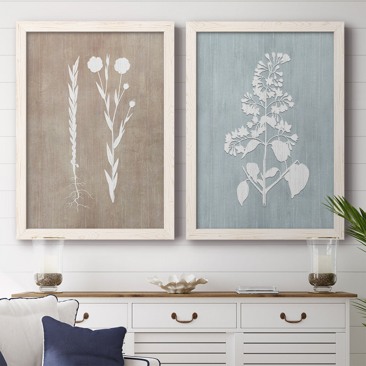 Set of two white barnwood framed canvas prints depicting a coordinated art pair of white botanical silhouettes on softly weathered neutral backgrounds rendered as rustic minimalist botanical prints above a dining room sideboard.