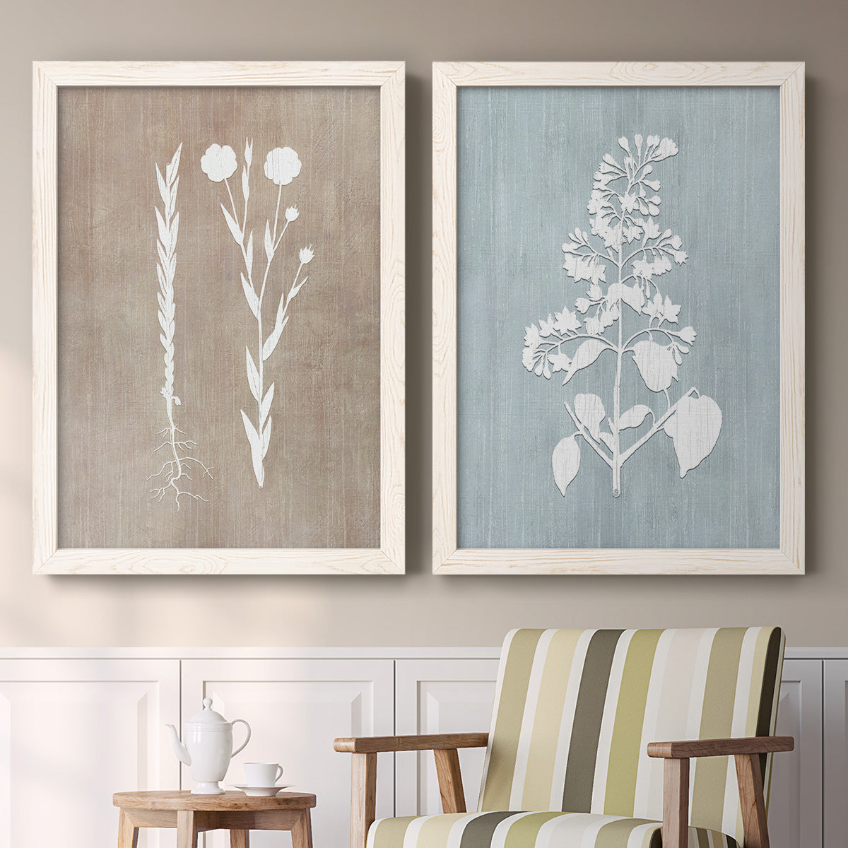 Set of two white barnwood framed canvas prints depicting two rustic minimalist botanical prints featuring white botanical silhouettes on softly weathered neutral backgrounds above a sideboard in a cozy sitting room.