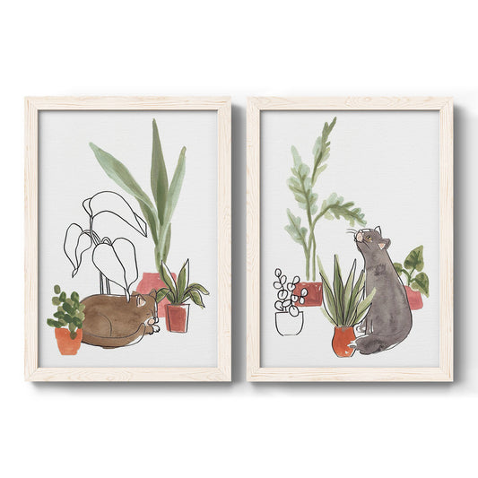 Set of two white barnwood framed canvas prints featuring two whimsical botanical animal illustrations featuring cats tucked among collections of potted houseplants.