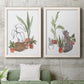 Set of two white barnwood framed canvas prints depicting a coordinated art pair of cats tucked among collections of potted houseplants rendered as whimsical botanical animal illustrations above a sofa in a modern living room.