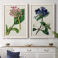 Set of two white barnwood framed canvas prints depicting a coordinated art pair of colorful flowering plant specimens rendered as antique botanical plate illustrations above a dining room sideboard.